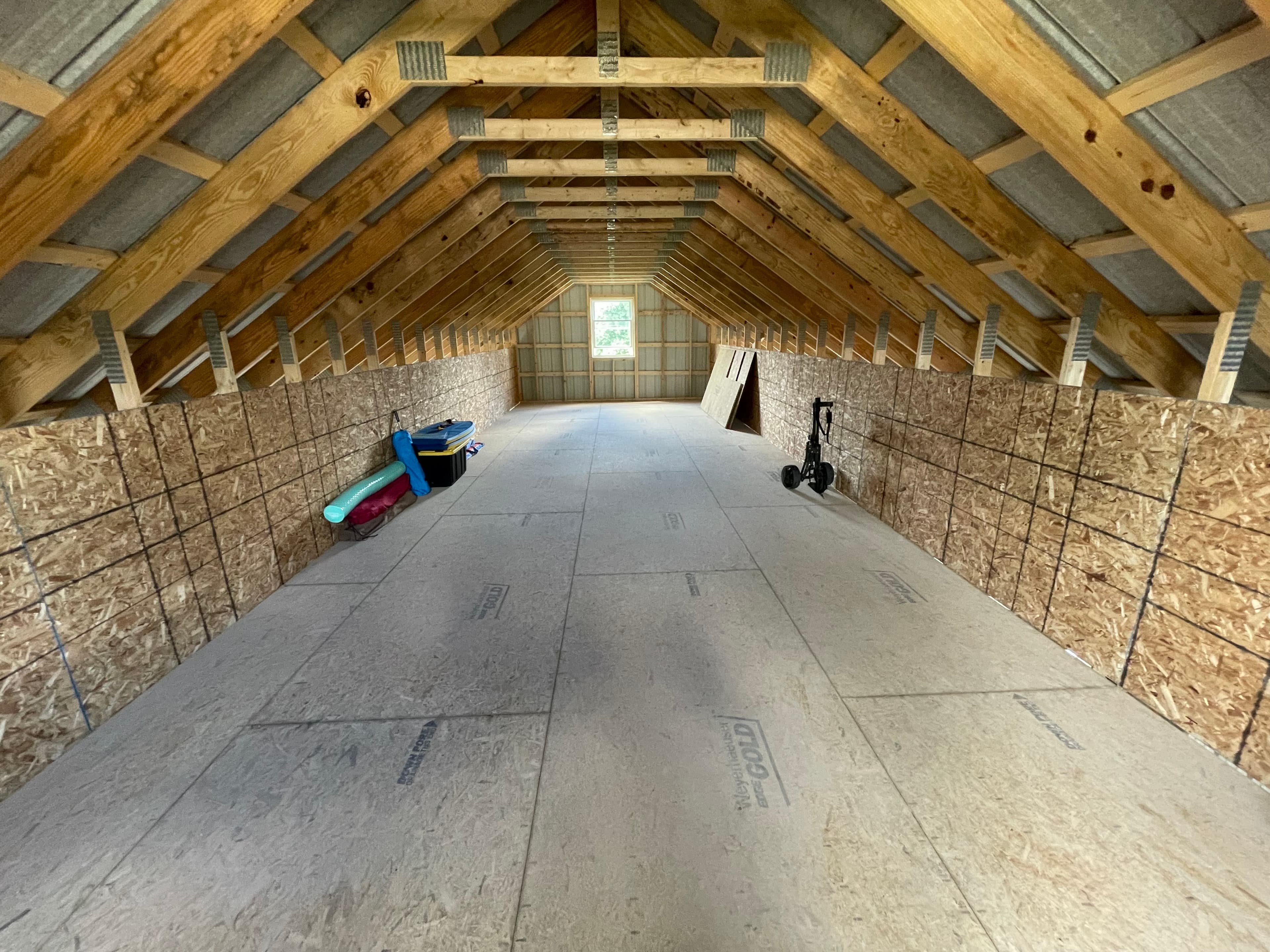 Unfinished attic with exposed wood beam framing, OSB walls, and foam board insulation installed