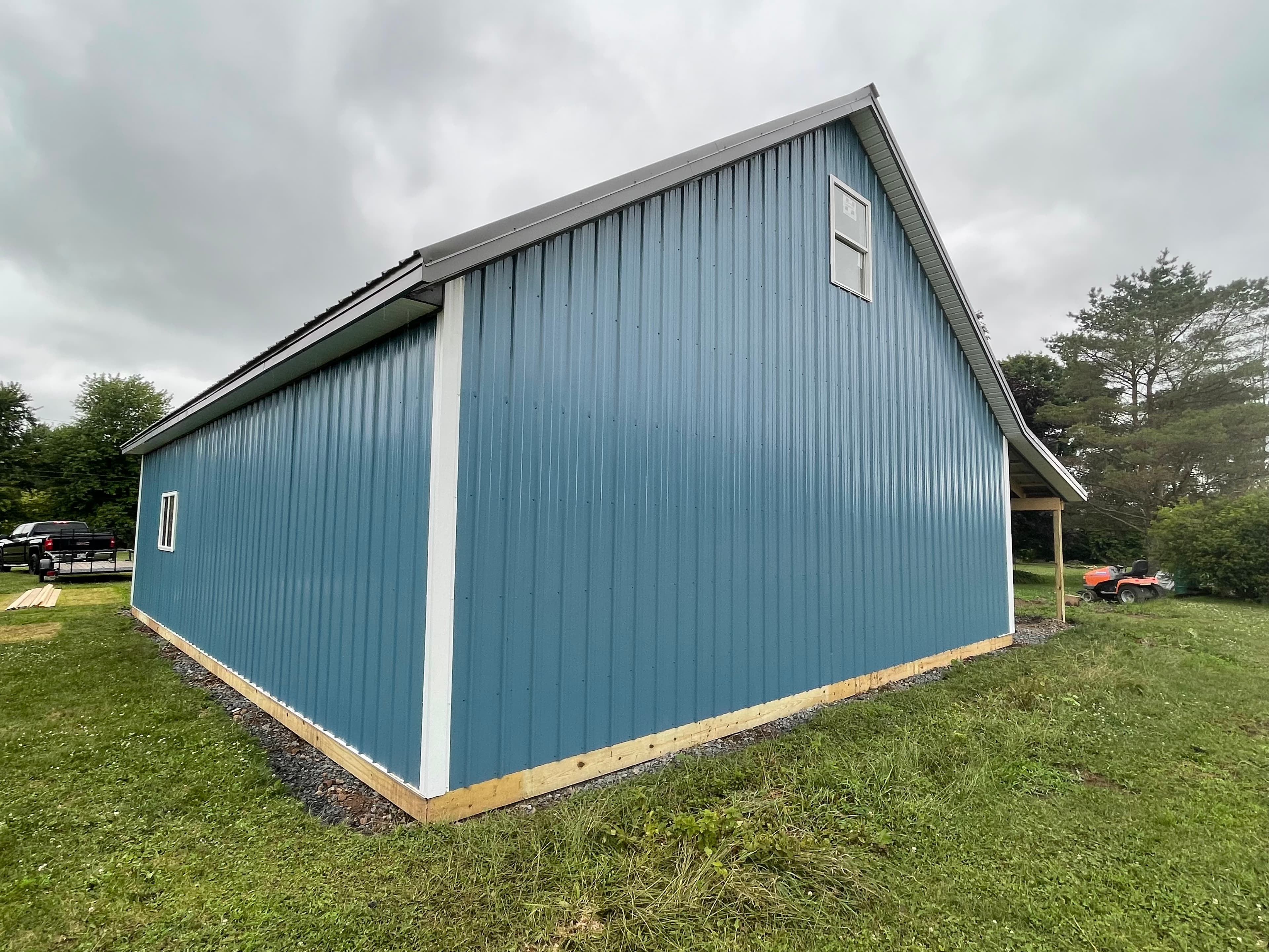 Blue corrugated metal pole barn with white trim and steep gabled roof