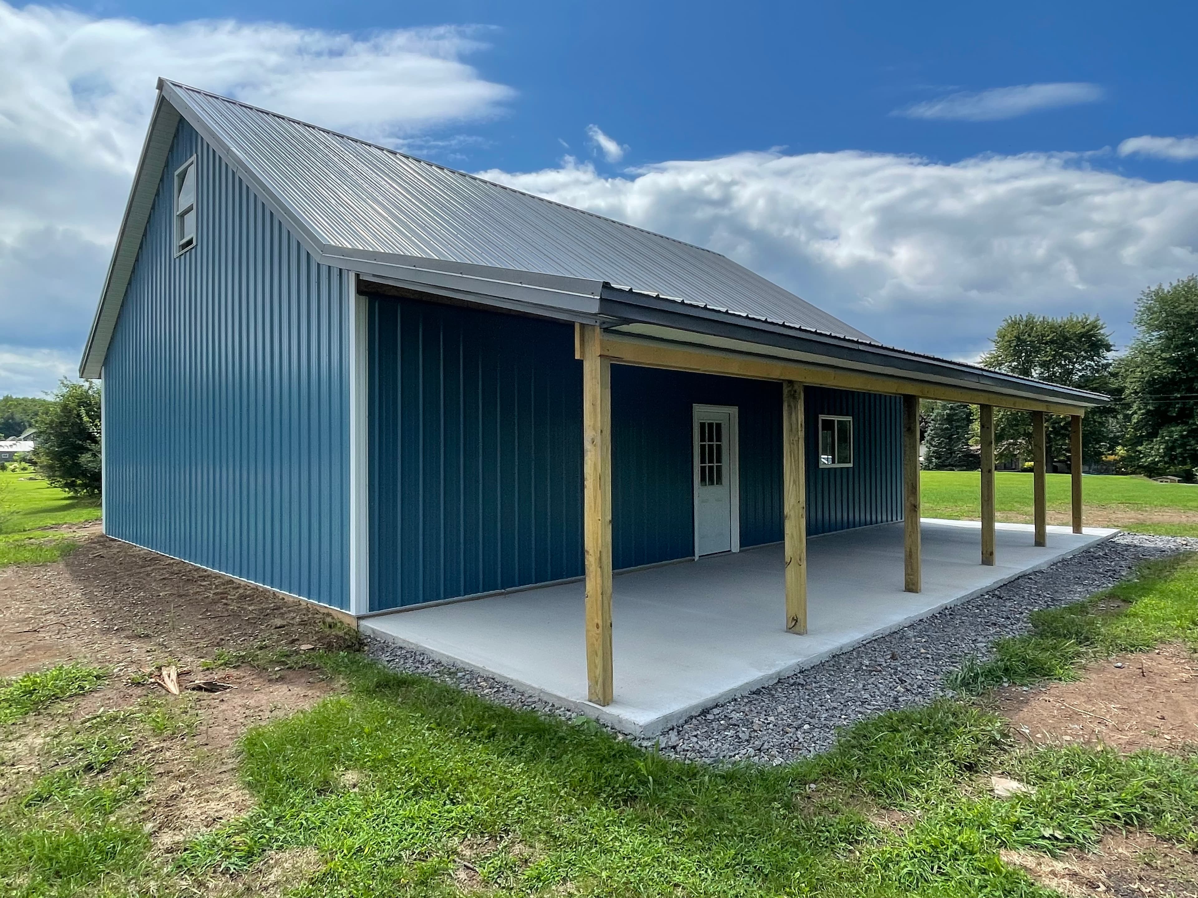 Blue metal pole barn with covered porch and concrete slab