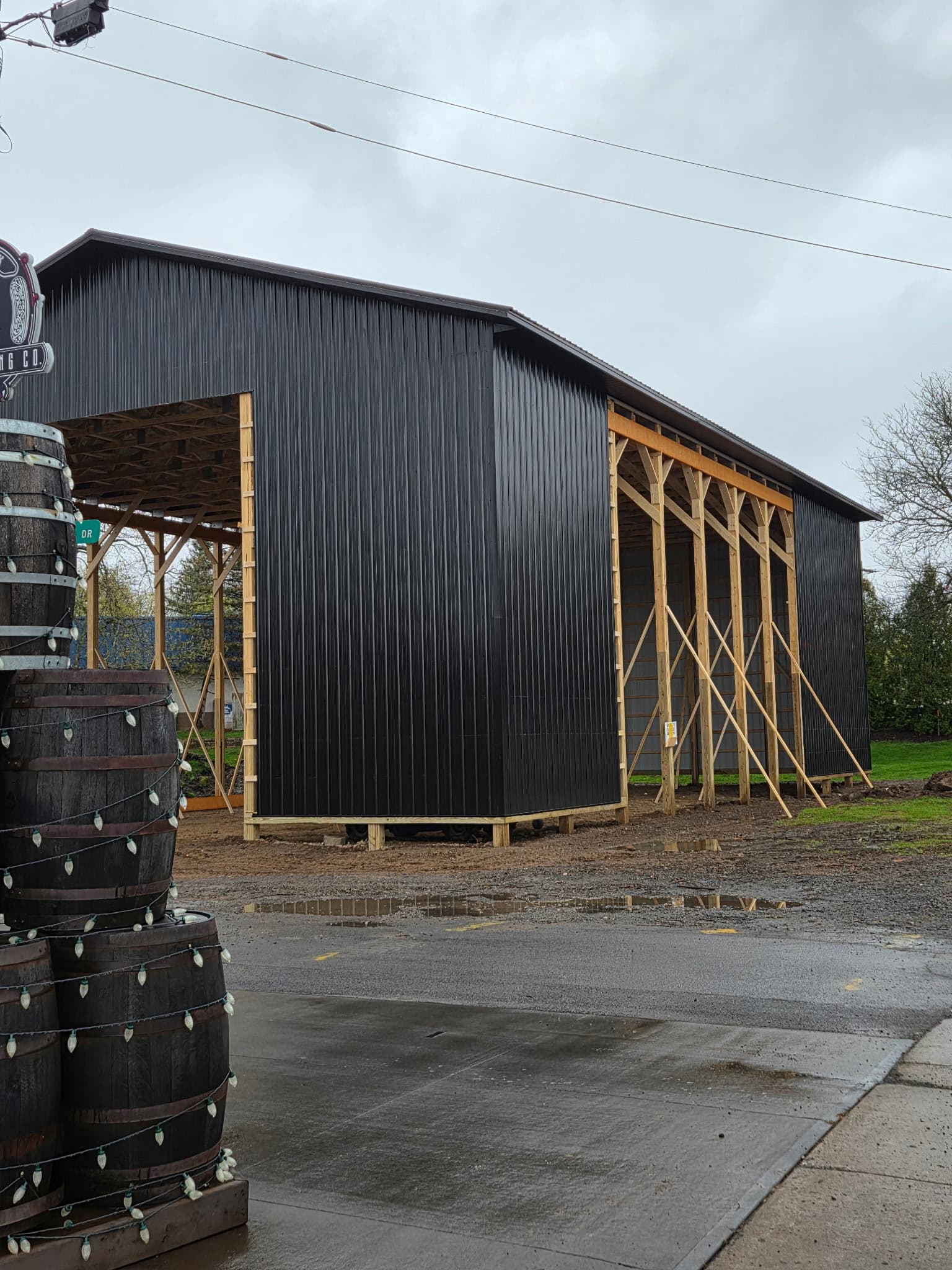 Gray metal pole barn with exposed wood framing and covered side area