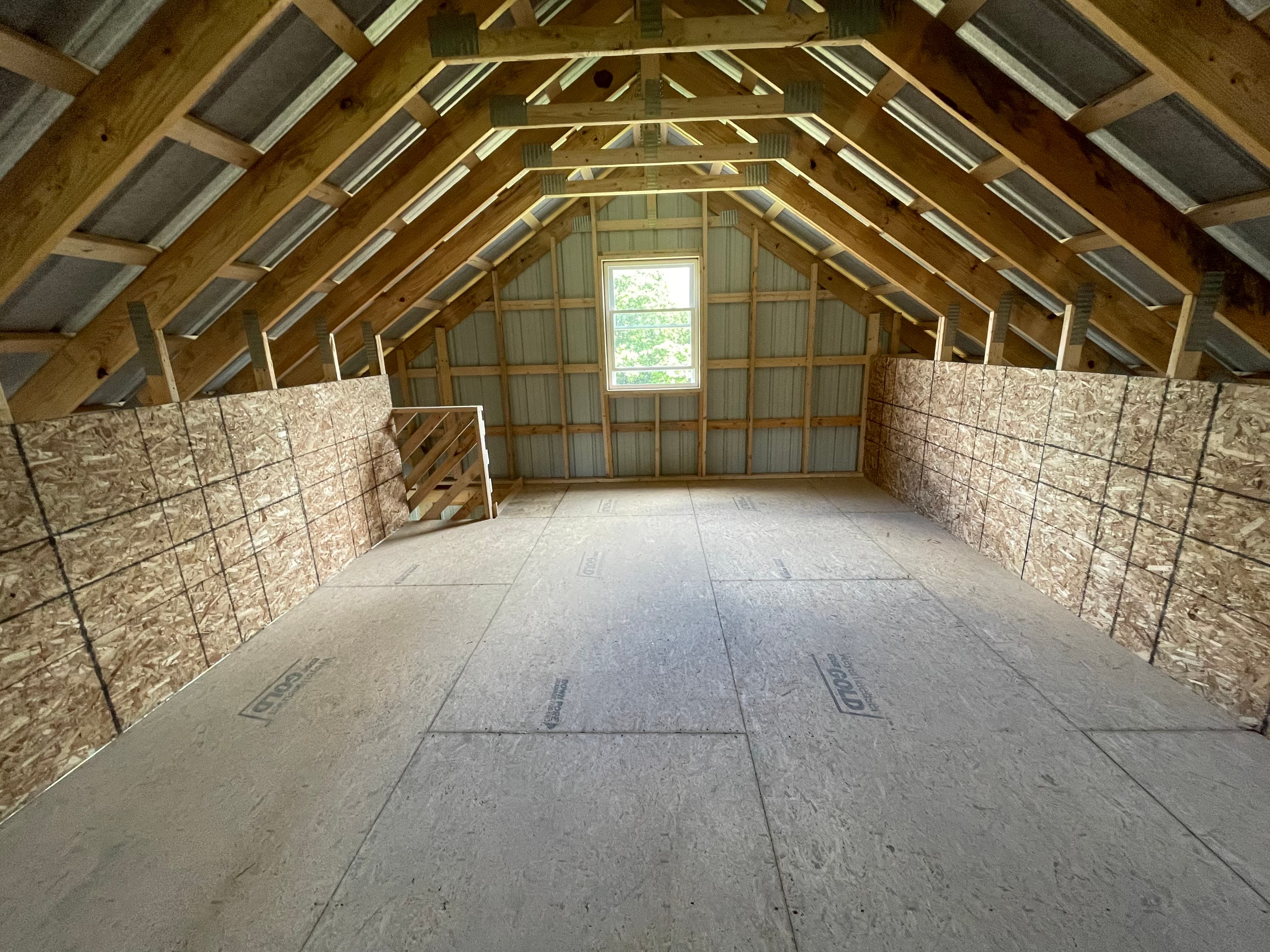 Attic space with exposed rafters, spray foam insulation on walls, and subflooring